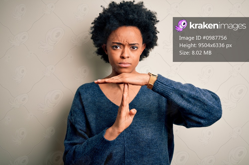 Young beautiful African American afro woman with curly hair wearing casual sweater Doing time out gesture with hands, frustrated and serious face