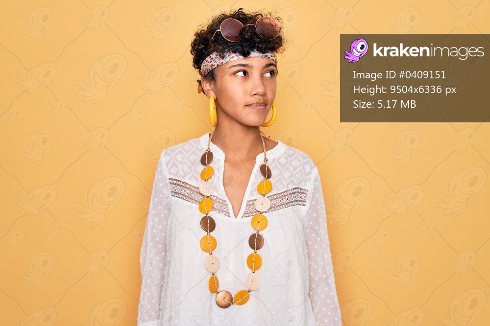Young beautiful african american afro hippie woman wearing sunglasses and accessories smiling looking to the side and staring away thinking.