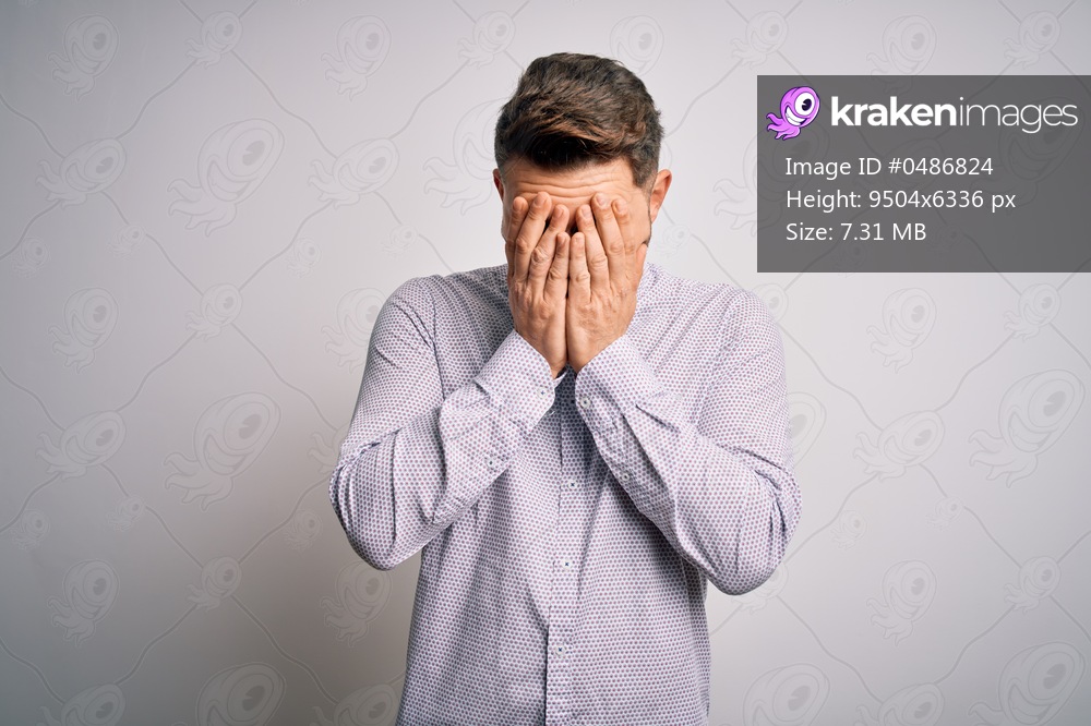 Young business man with blue eyes standing over isolated background with sad expression covering face with hands while crying. Depression concept.