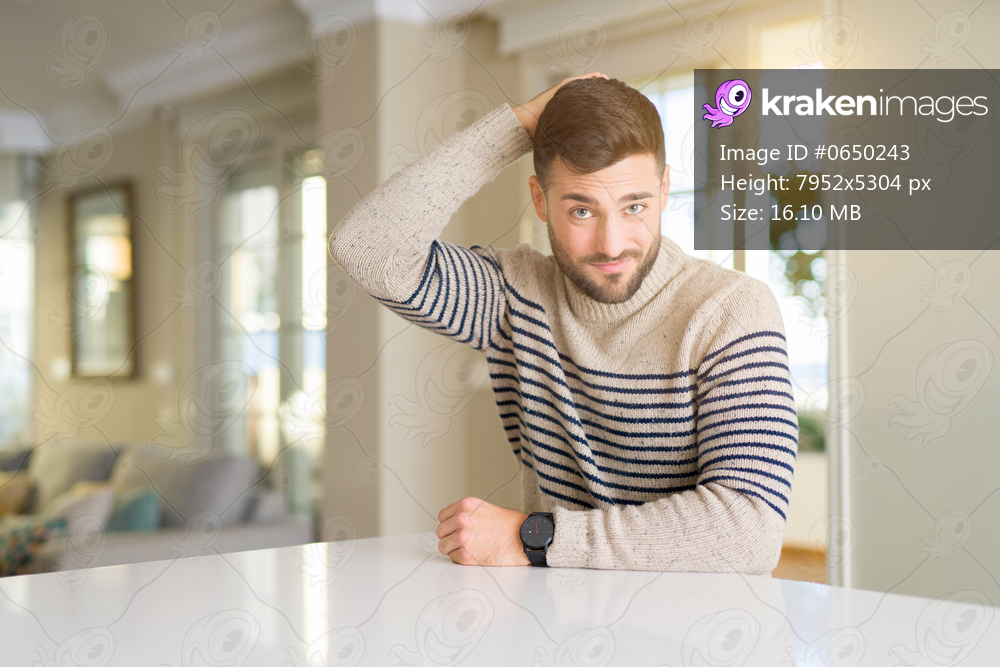 Young handsome man at home confuse and wonder about question. Uncertain with doubt, thinking with hand on head. Pensive concept.