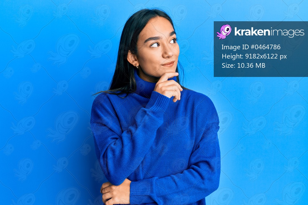 Young asian woman wearing casual winter sweater with hand on chin thinking about question, pensive expression. smiling and thoughtful face. doubt concept. 