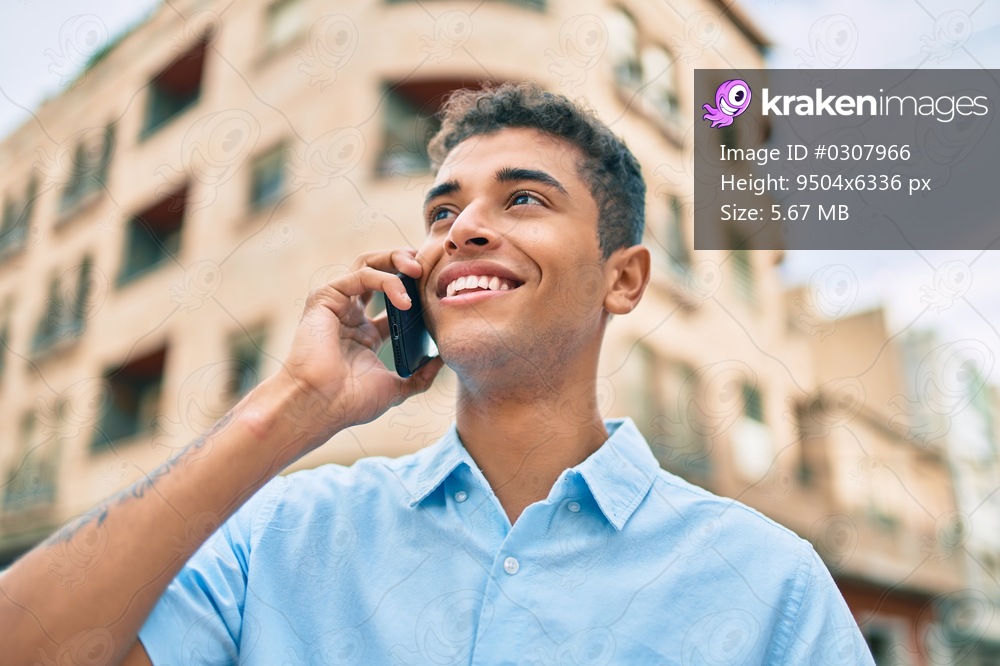 Young latin man smiling happy talking on the smartphone walking at the city.