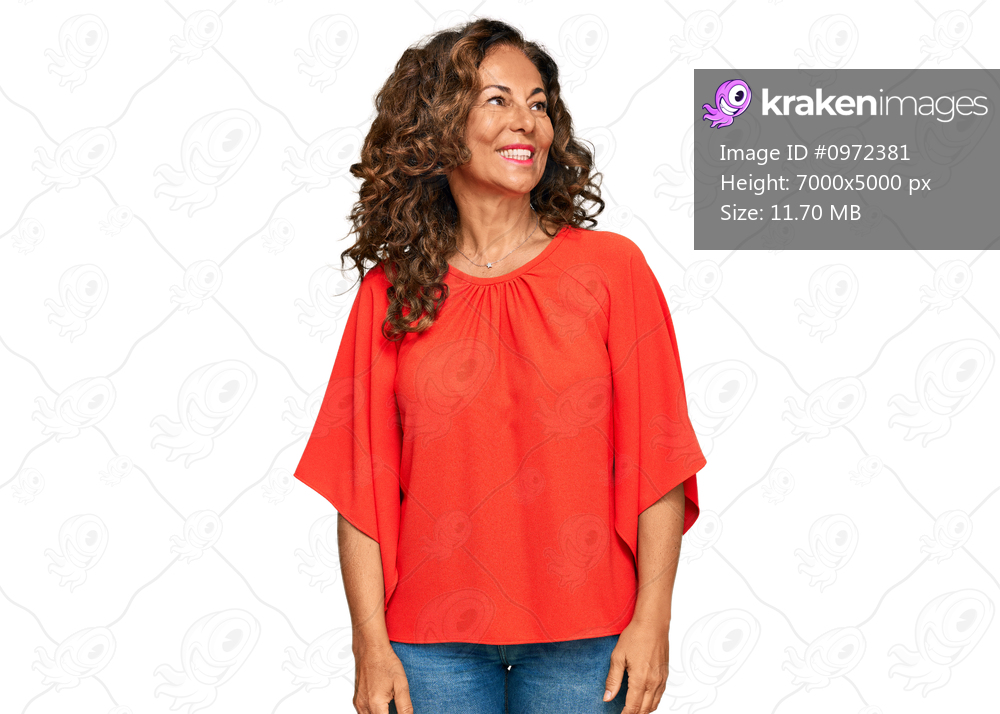 Middle age hispanic woman wearing casual clothes looking away to side with smile on face, natural expression. laughing confident. 