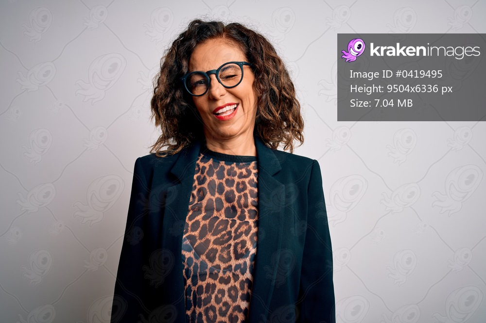 Middle age brunette business woman wearing glasses standing over isolated white background winking looking at the camera with sexy expression, cheerful and happy face.