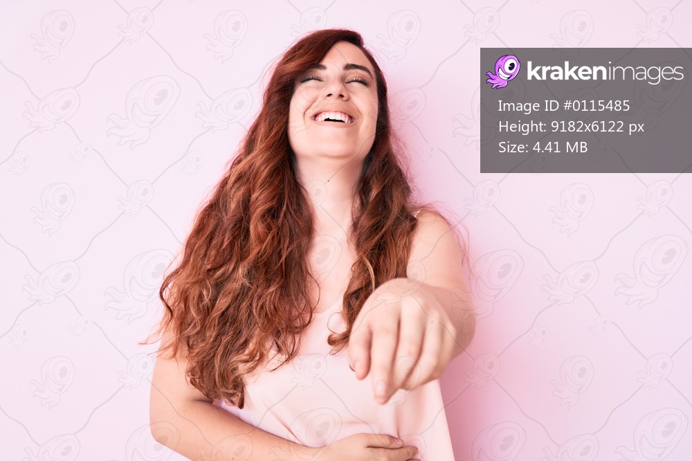 Young beautiful woman wearing casual clothes laughing at you, pointing finger to the camera with hand over body, shame expression 