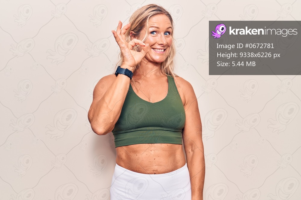 Middle age caucasian blonde woman wearing sportswear smiling positive doing ok sign with hand and fingers. successful expression. 