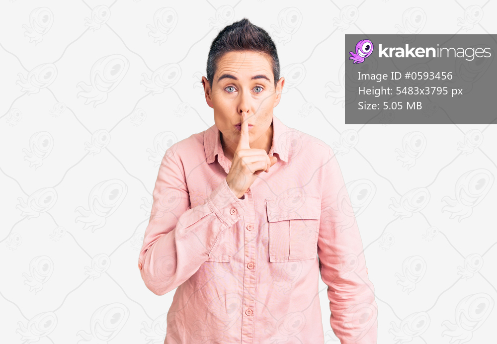 Young woman with short hair wearing casual clothes asking to be quiet with finger on lips. silence and secret concept. 