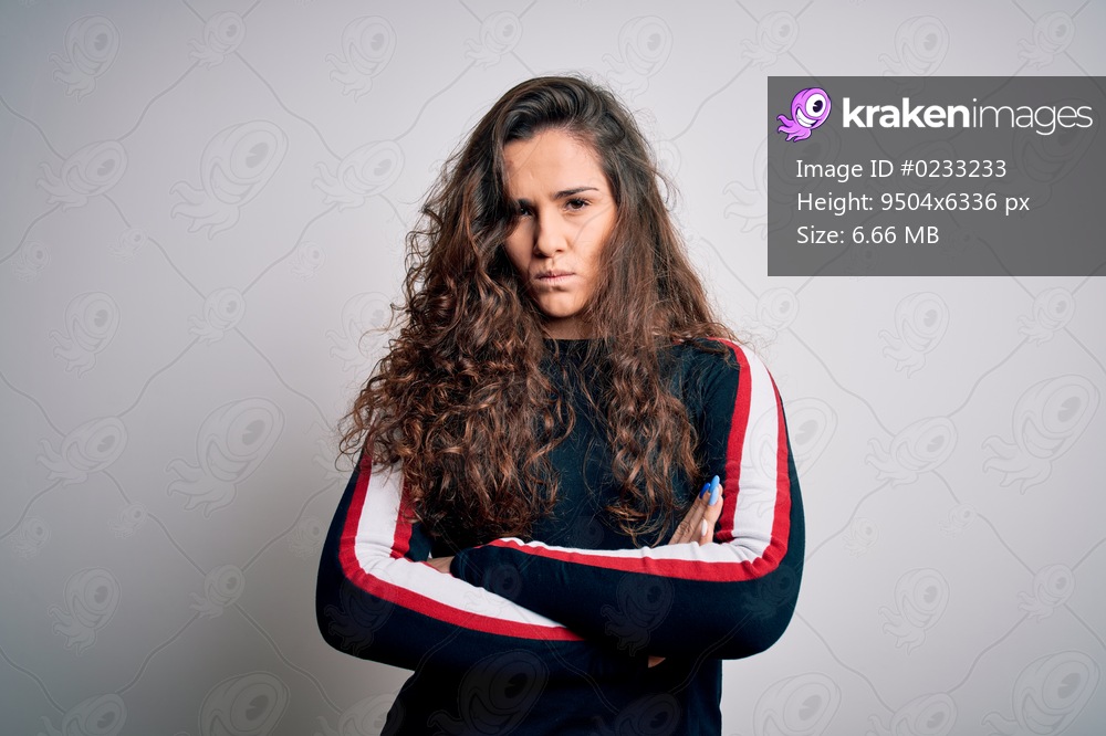 Young beautiful woman with curly hair wearing casual sweater over isolated white background skeptic and nervous, disapproving expression on face with crossed arms. Negative person.