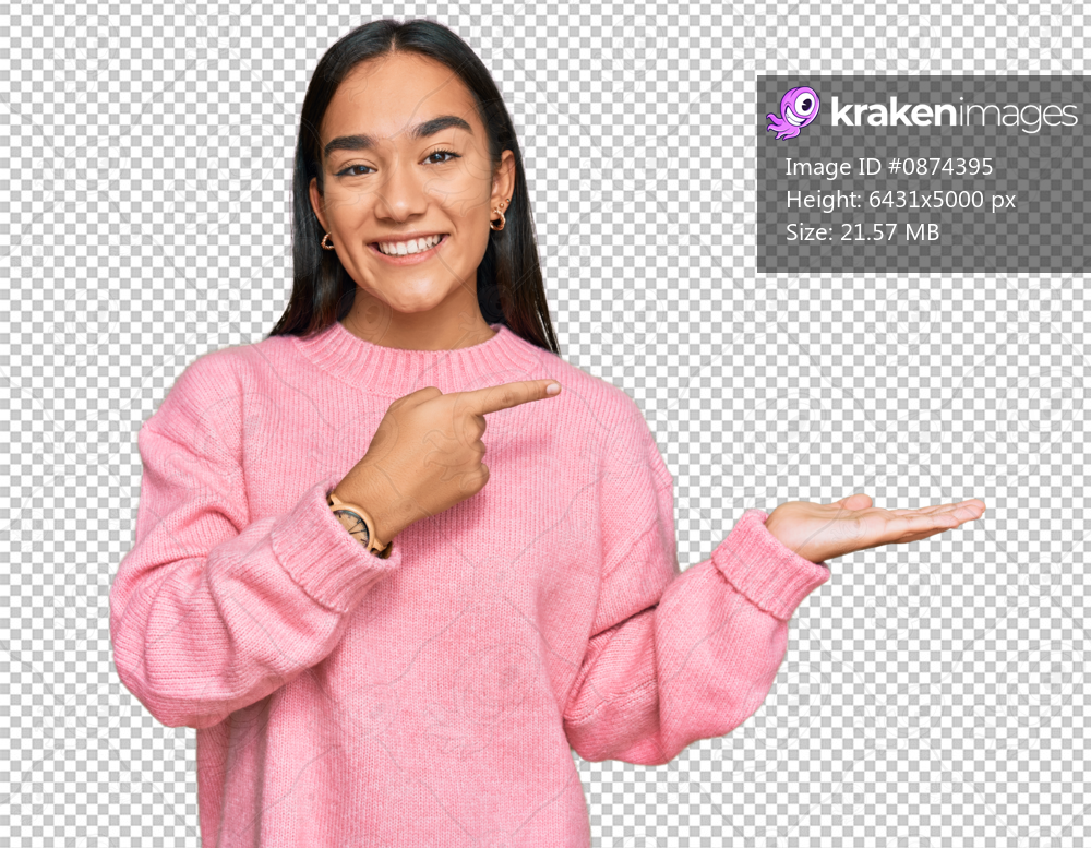 Young asian woman wearing casual winter sweater amazed and smiling to the camera while presenting with hand and pointing with finger.