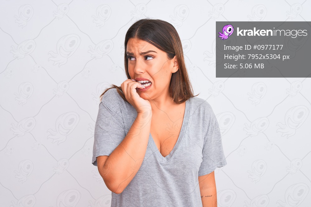 Portrait of beautiful young woman standing over isolated white background looking stressed and nervous with hands on mouth biting nails. Anxiety problem.