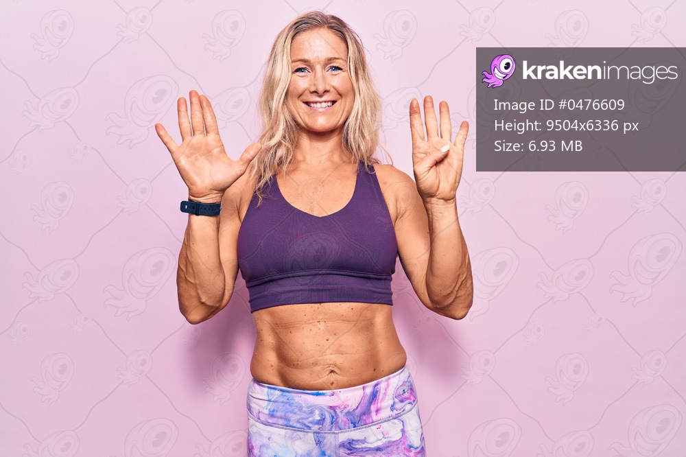 Middle age caucasian blonde woman wearing sportswear over pink background showing and pointing up with fingers number nine while smiling confident and happy. 