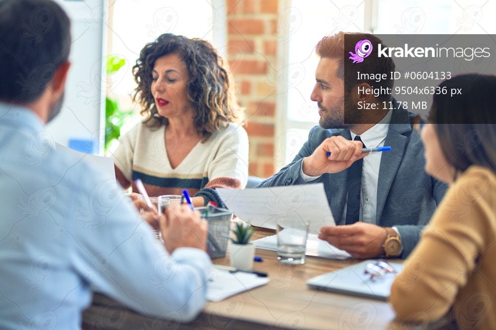 Group of business workers working together. Sitting on desk reading documents at the office