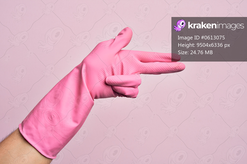 Hand of caucasian young man with cleaning glove over isolated pink background gesturing fire gun weapon with fingers, aiming shoot symbol