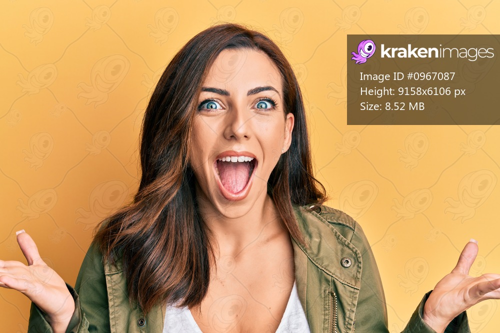 Young brunette woman wearing casual clothes over yellow background celebrating crazy and amazed for success with open eyes screaming excited. 