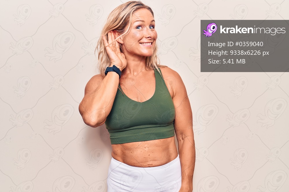 Middle age caucasian blonde woman wearing sportswear smiling with hand over ear listening an hearing to rumor or gossip. deafness concept. 