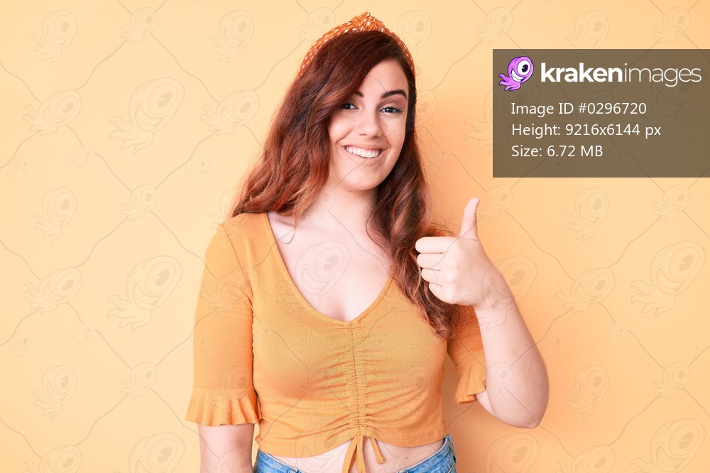 Young beautiful woman wearing casual clothes doing happy thumbs up gesture with hand. approving expression looking at the camera showing success. 