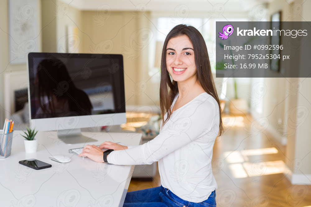 Young woman smiling working using computer and showing a blank screen on the background
