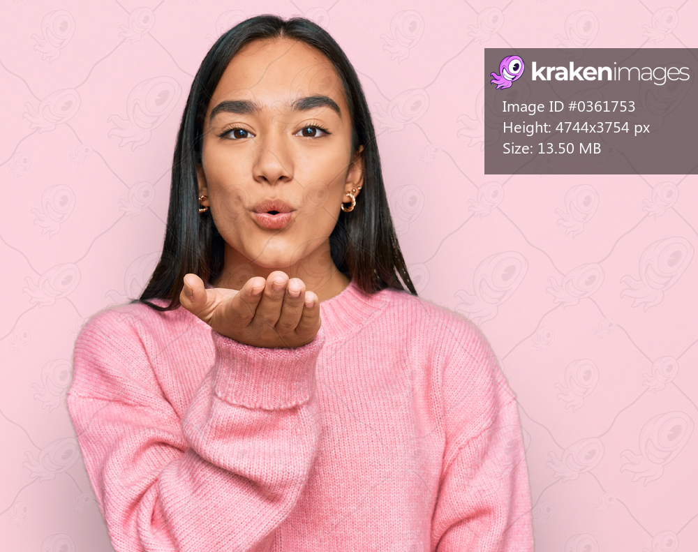 Young asian woman wearing casual winter sweater looking at the camera blowing a kiss with hand on air being lovely and sexy. love expression. 