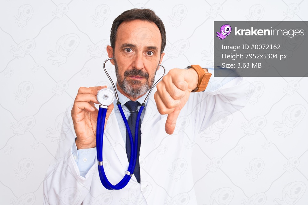 Middle age doctor man using stethoscope standing over isolated white background with angry face, negative sign showing dislike with thumbs down, rejection concept