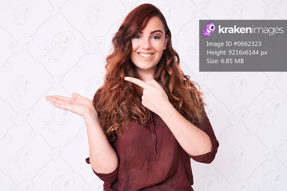 Young beautiful woman wearing casual clothes amazed and smiling to the camera while presenting with hand and pointing with finger. 