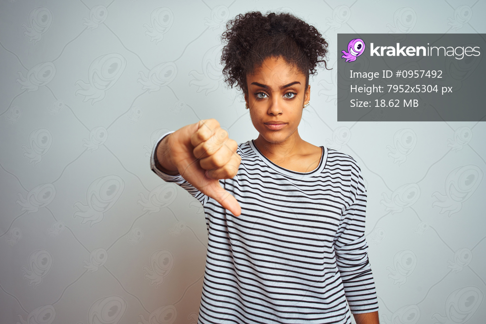 African american woman wearing navy striped t-shirt standing over isolated white background looking unhappy and angry showing rejection and negative with thumbs down gesture. Bad expression.