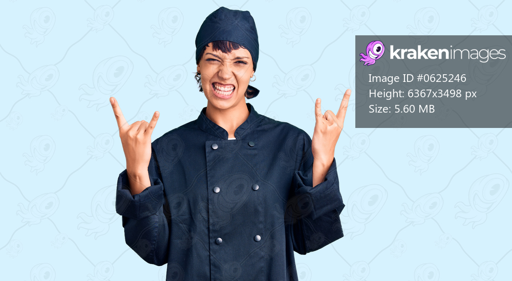 Young brunette woman with short hair wearing professional cook uniform shouting with crazy expression doing rock symbol with hands up. music star. heavy concept. 