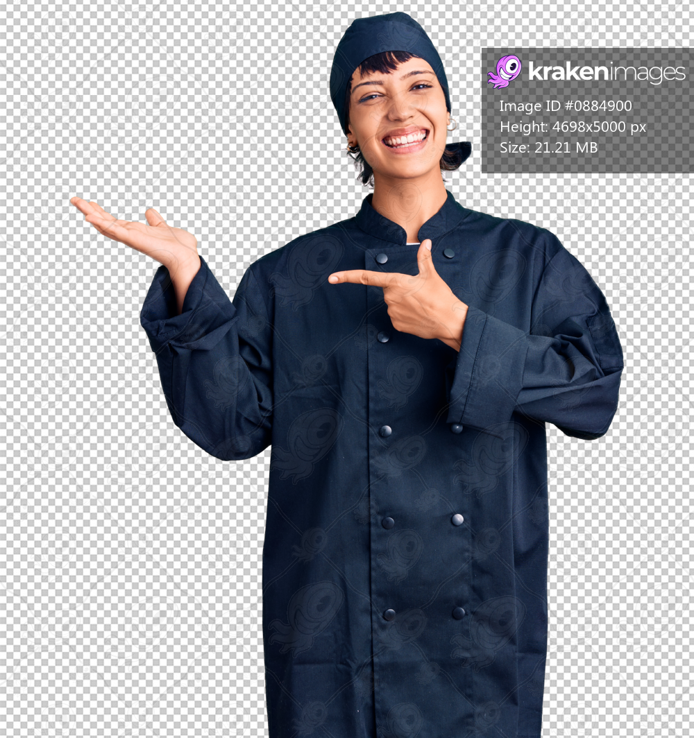 Young brunette woman with short hair wearing professional cook uniform amazed and smiling to the camera while presenting with hand and pointing with finger.