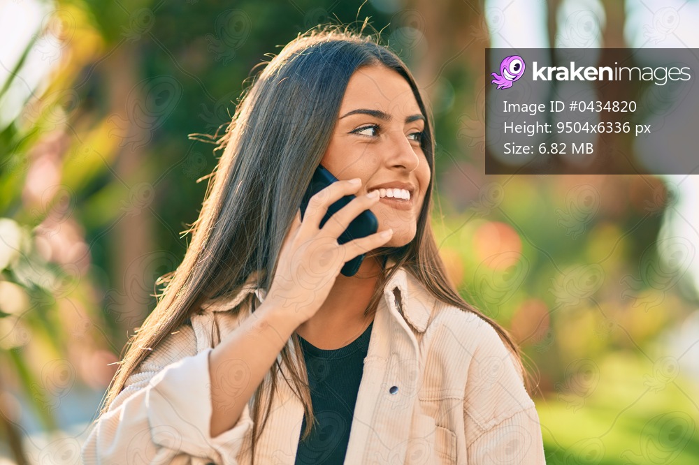 Young hispanic girl smiling happy talking on the smartphone at the park.