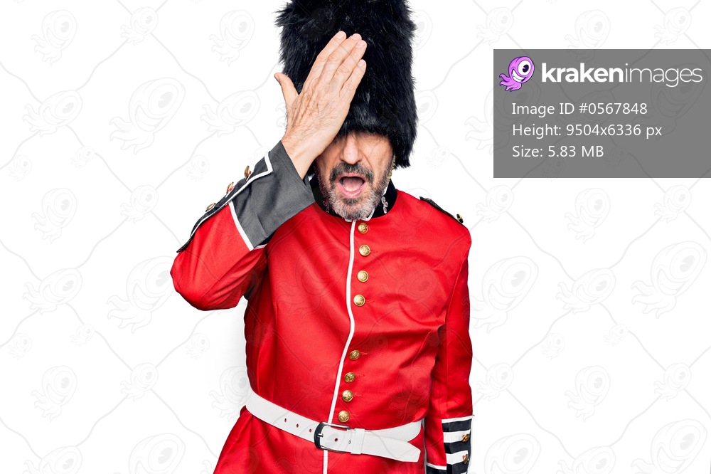 Middle age handsome wales guard man wearing traditional uniform over white background surprised with hand on head for mistake, remember error. Forgot, bad memory concept.