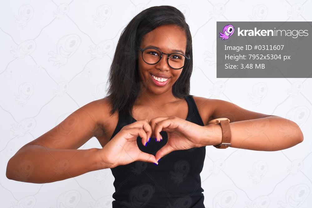 Beautiful young african american woman wearing glasses over isolated background smiling in love showing heart symbol and shape with hands. Romantic concept.