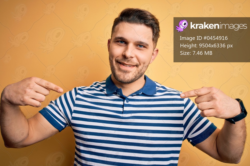 Young man with blue eyes wearing casual striped t-shirt over yellow background looking confident with smile on face, pointing oneself with fingers proud and happy.