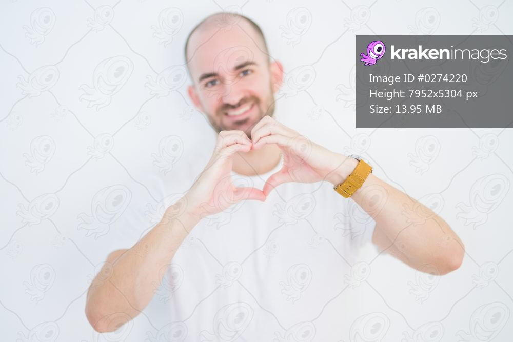 Young bald man over white isolated background smiling in love showing heart symbol and shape with hands. Romantic concept.
