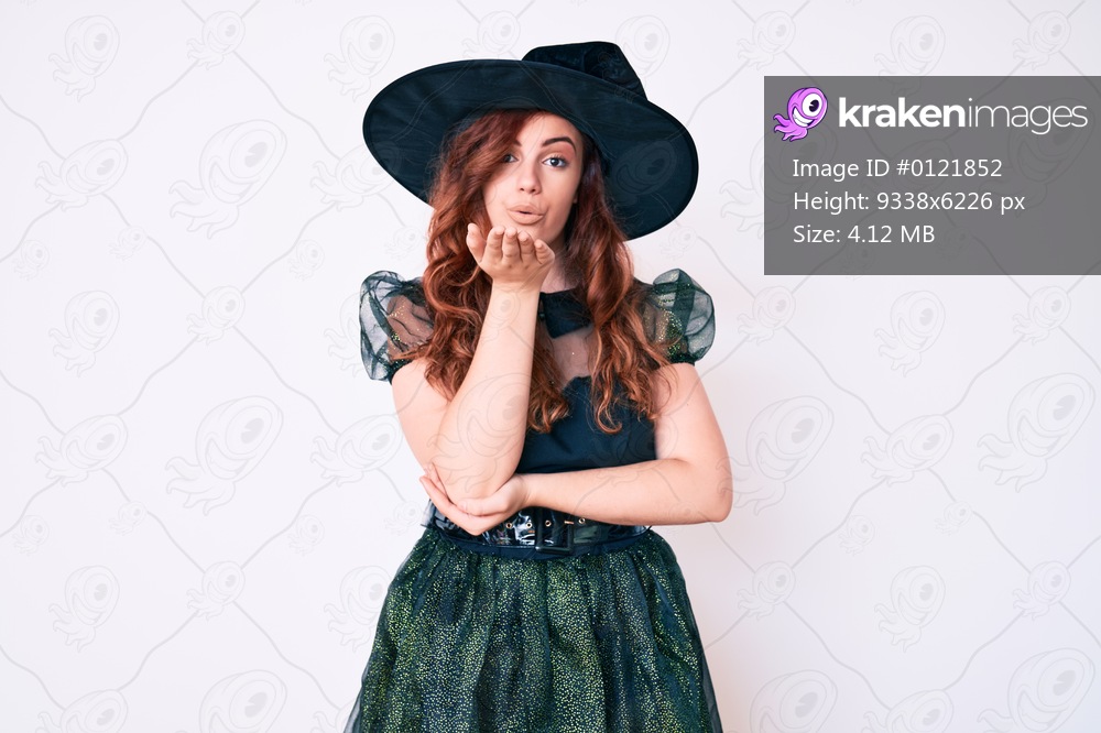 Young beautiful woman wearing witch halloween costume looking at the camera blowing a kiss with hand on air being lovely and sexy. love expression. 