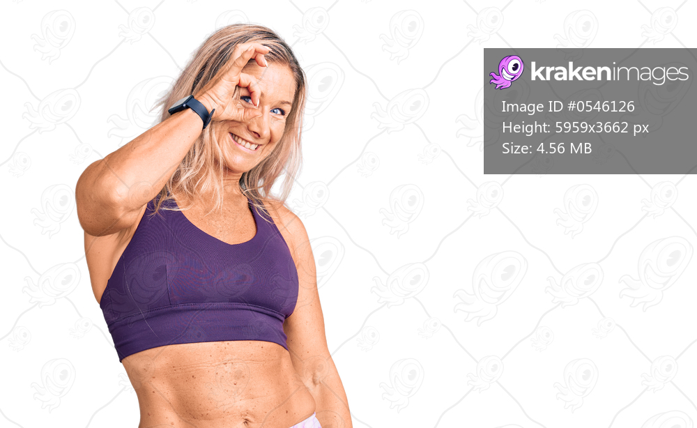 Middle age fit blonde woman wearing sportswear smiling happy doing ok sign with hand on eye looking through fingers 