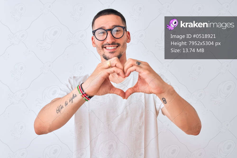 Young handsome man wearing glasses and standing over isolated background smiling in love showing heart symbol and shape with hands. Romantic concept.
