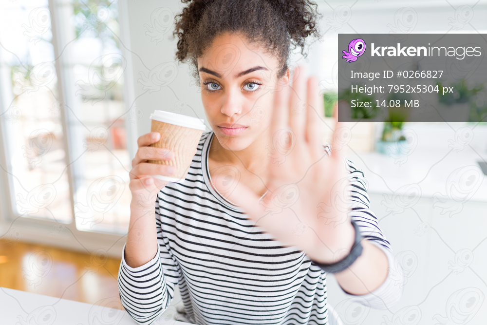 Young african american girl drinking a coffee on a take away paper cup with open hand doing stop sign with serious and confident expression, defense gesture