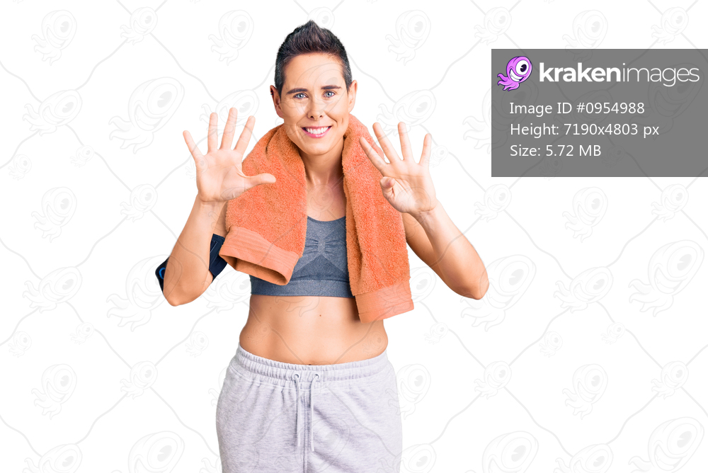 Young woman with short hair wearing sportswear and towel using smartphone showing and pointing up with fingers number nine while smiling confident and happy. 