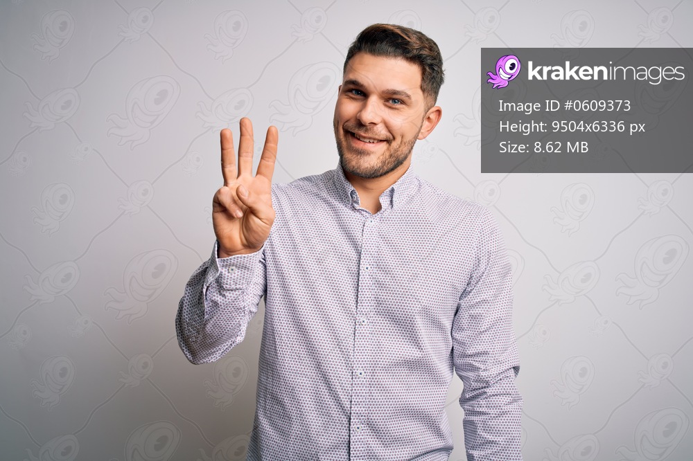 Young business man with blue eyes standing over isolated background showing and pointing up with fingers number three while smiling confident and happy.