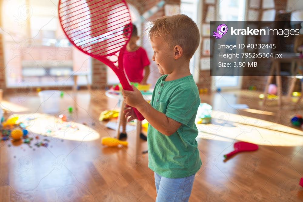 Adorable toddlers playing around lots of toys at kindergarten