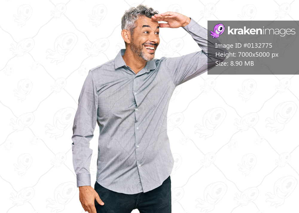 Middle age grey-haired man wearing casual clothes very happy and smiling looking far away with hand over head. searching concept. 