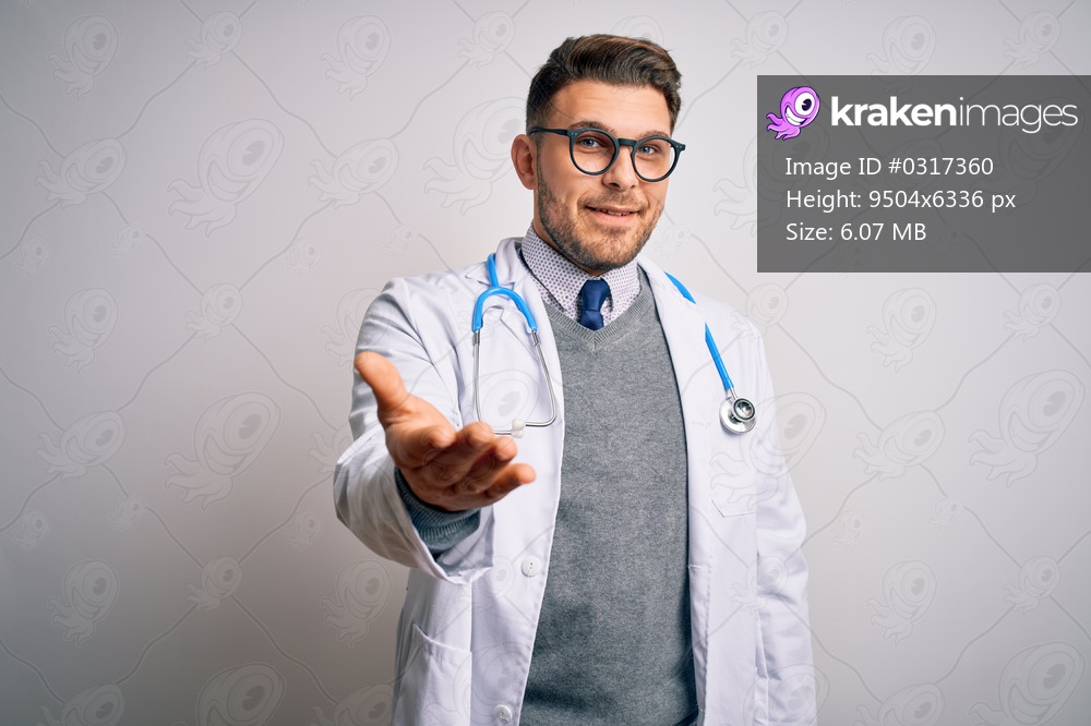 Young doctor man with blue eyes wearing medical coat and stethoscope over isolated background smiling cheerful offering palm hand giving assistance and acceptance.
