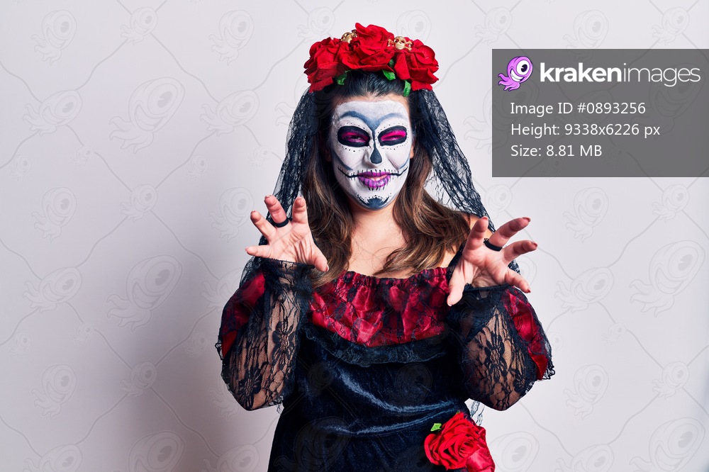 Young woman wearing day of the dead costume over white smiling funny doing claw gesture as cat, aggressive and sexy expression 
