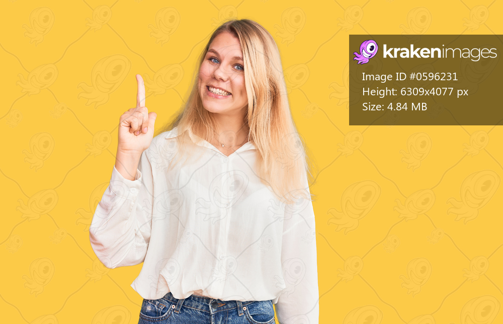 Young beautiful blonde woman wearing casual shirt pointing finger up with successful idea. exited and happy. number one. 