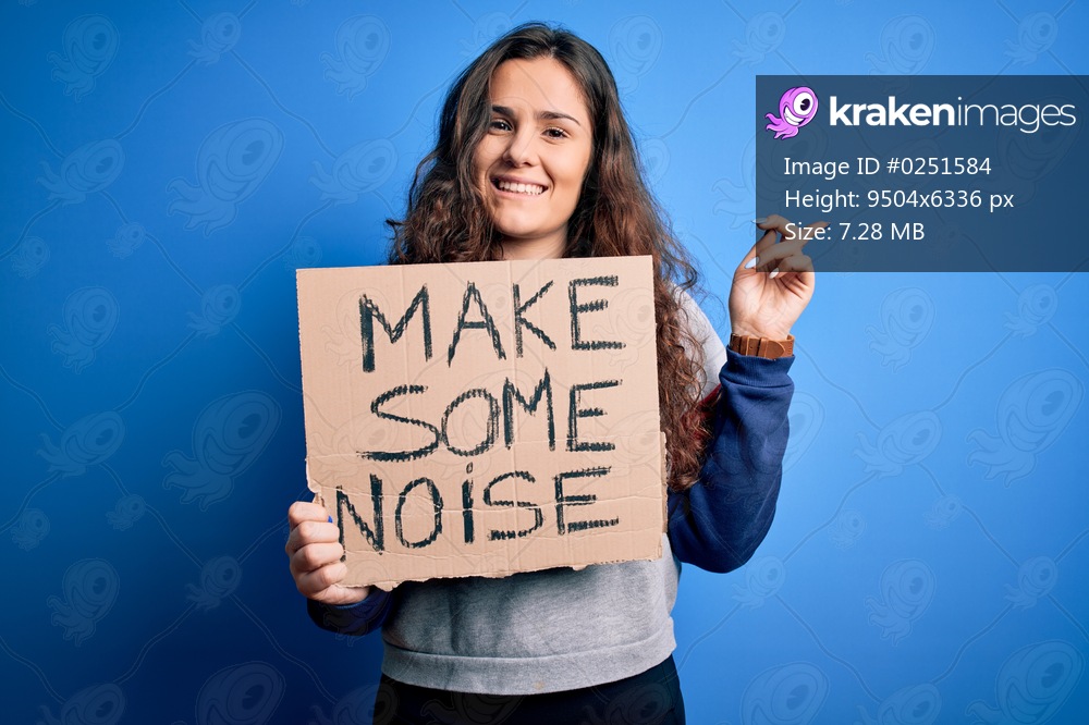 Beautiful activist woman holding banner with make some noise message over blue background very happy pointing with hand and finger to the side