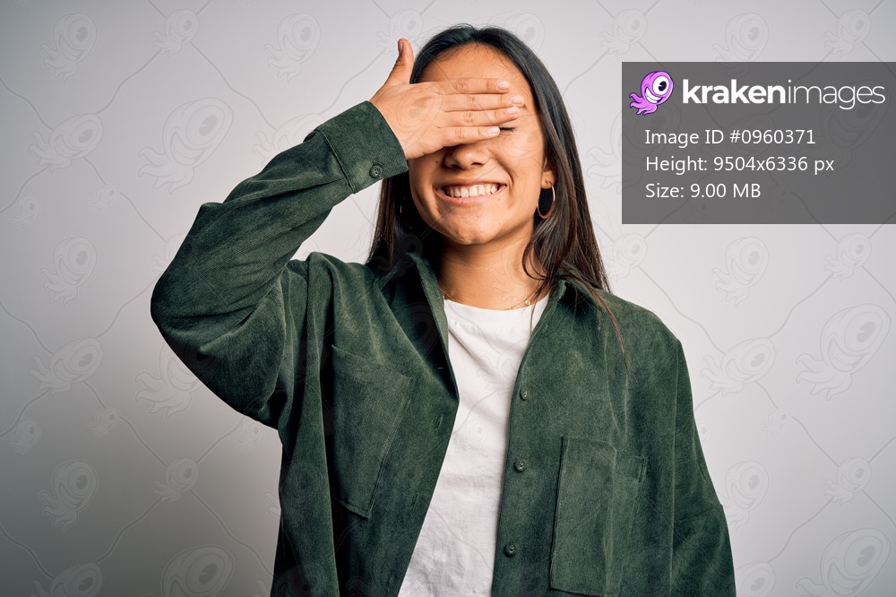 Young beautiful asian woman wearing casual shirt standing over isolated white background smiling and laughing with hand on face covering eyes for surprise. Blind concept.
