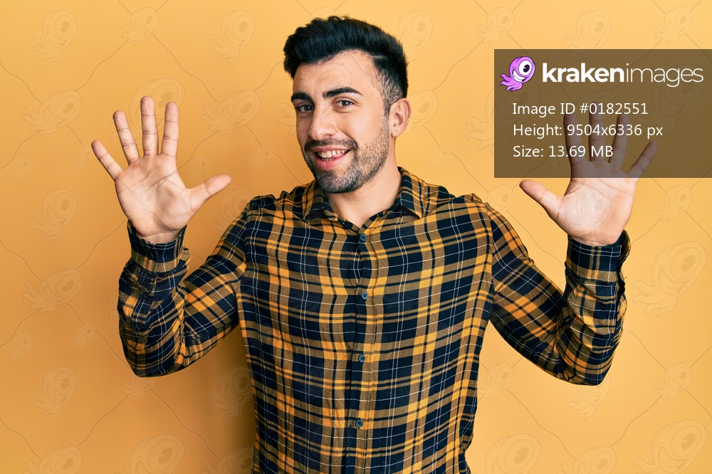 Young hispanic man wearing casual clothes showing and pointing up with fingers number ten while smiling confident and happy. 