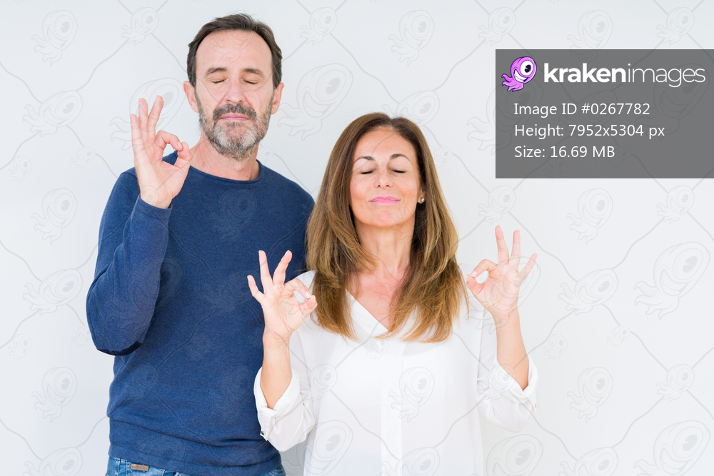Beautiful middle age couple in love over isolated background relax and smiling with eyes closed doing meditation gesture with fingers. Yoga concept.