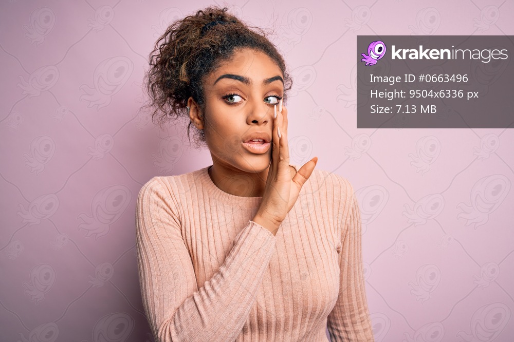 Young beautiful african american girl wearing casual sweater standing over pink background hand on mouth telling secret rumor, whispering malicious talk conversation