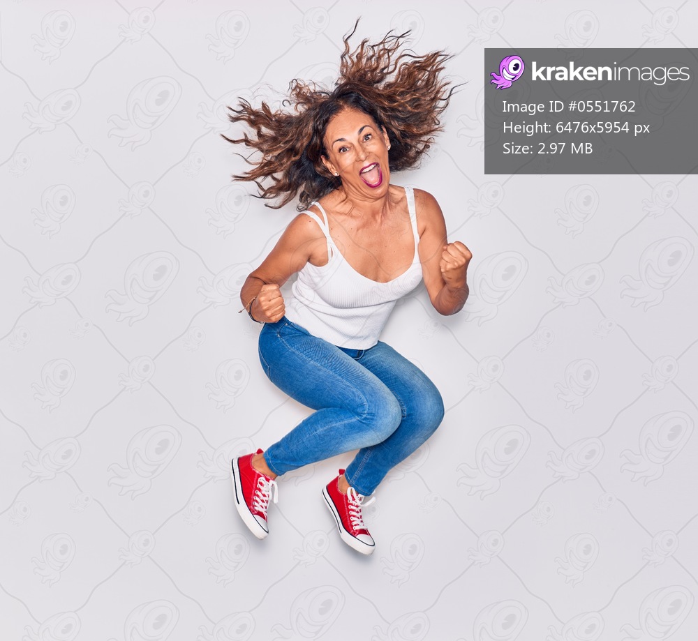 Middle age beautiful hispanic woman wearing casual clothes smiling happy. Jumping with smile on face doing winner gesture with fists up over isolated white background