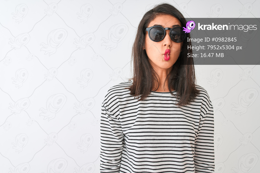 Chinese woman wearing striped t-shirt and sunglasses standing over isolated white background making fish face with lips, crazy and comical gesture. Funny expression.